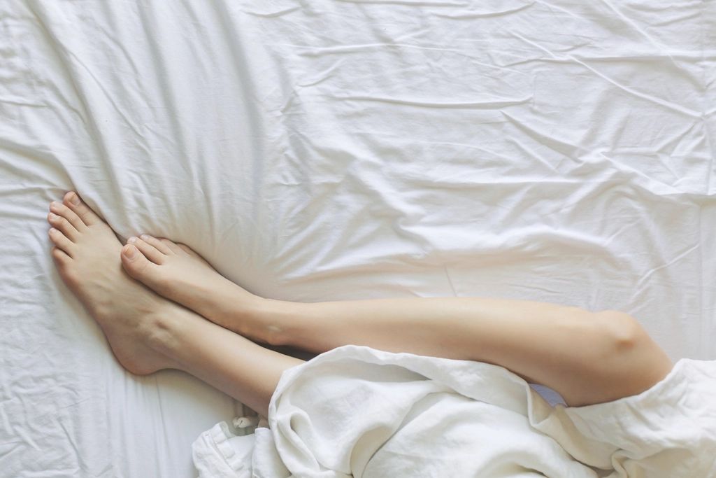 Bare legs stretched out on rumpled white sheets.