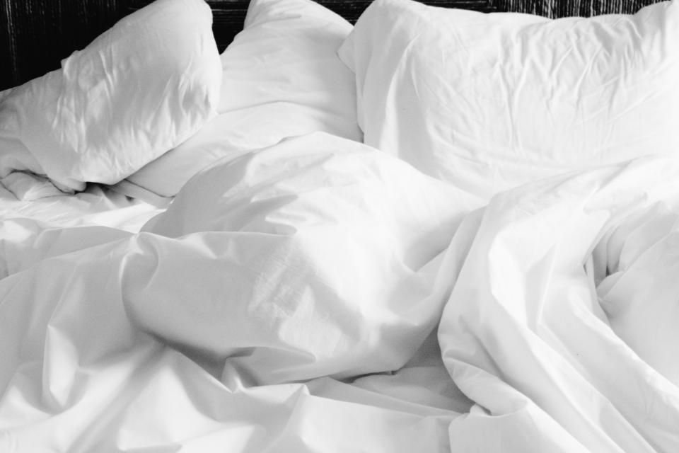 Rumpled white pillows and sheets on an unmade bed.